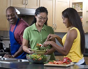 Family making salad in kitchen.