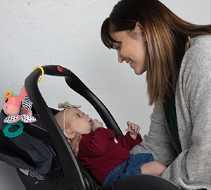 Woman placing baby in infant carrier.