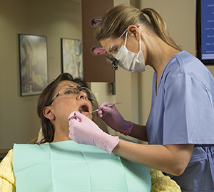 Dental health care provider cleaning woman's teeth.